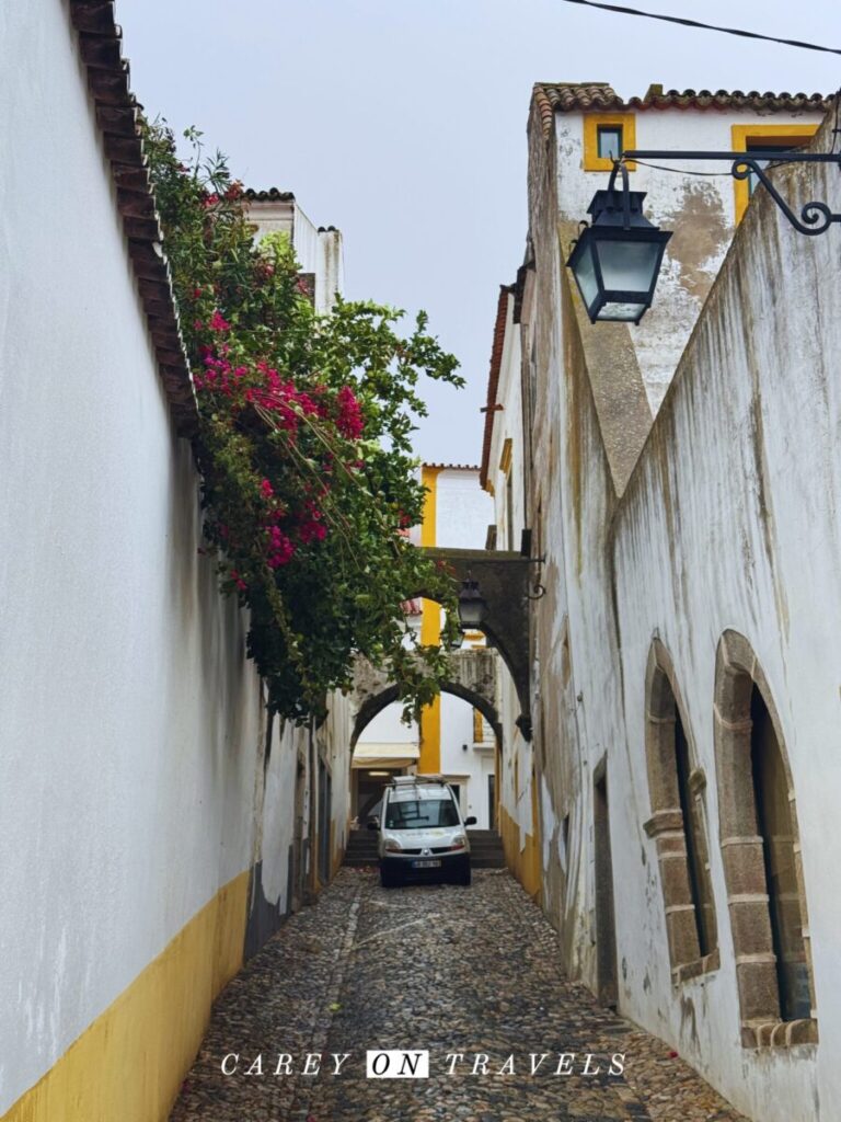 Cars driving through a narrow arch in Evora, Portugal